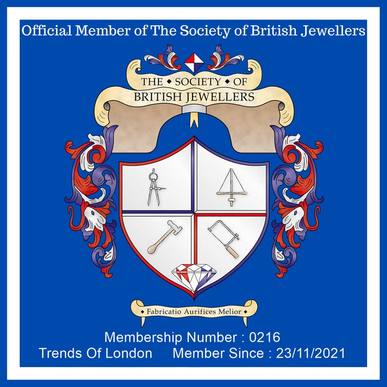 May include: A blue and white emblem for The Society of British Jewellers. The emblem features a shield divided into four quadrants, each with a different jewelry-making tool. Text includes "Official Member," "Fabricatio Aurifices Melior," and membership details.