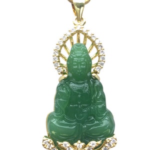 Peut inclure: Un collier avec un pendentif en or représentant une figurine de Bouddha en jade vert. Le Bouddha est assis en position de lotus et est entouré d'un halo de cristaux transparents. Le pendentif est attaché à une chaîne en or.