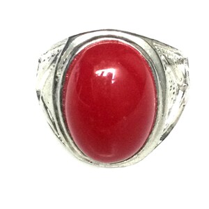 May include: A silver ring with a large, oval-shaped, red gemstone.