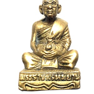 Peut inclure: Une statue dorée d'un moine assis portant des lunettes. La statue est sur un socle avec du texte thaïlandais.