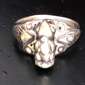 May include: A silver ring with an octopus design. The octopus is detailed and has a textured surface. The ring is a statement piece and would make a great gift.