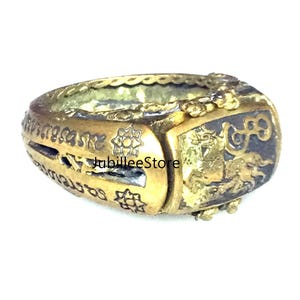 Peut inclure: Une bague en or avec des détails complexes et un motif noir et or. La bague a un motif en relief sur le dessus et est inscrite de texte dans une langue étrangère.