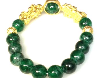 May include: A beaded bracelet featuring large, round, dark green beads. The bracelet includes gold-colored decorative elements, including two dragon-like figures and a central circular piece. The beads have a marbled appearance.