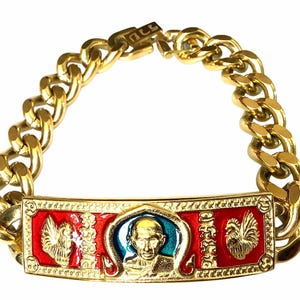 May include: Gold-toned bracelet with a thick chain design. The centerpiece features a red and gold rectangular plaque with a central image of a person and rooster figures. The bracelet is a bold accessory.