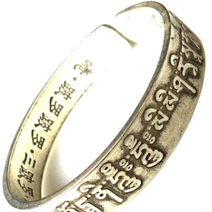 Puede incluir: Pulsera de plata con una inscripción en escritura tibetana y caracteres chinos. La inscripción dice "2500 010 010 མི་མི་ཤརས 吨·跛罗跛罗·三跛罗".