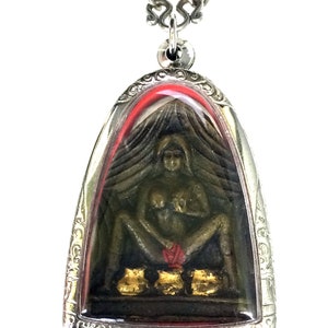 Op de afbeelding: Een zilveren hangerketting met een bronskleurig beeld van een zittende figuur in een heldere, gewelfde behuizing. Het beeld heeft een rode doek en drie goudkleurige potten aan de basis. De hanger hangt aan een zilveren ketting.