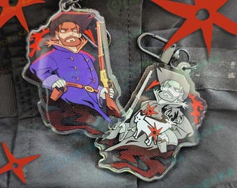 May include: Two acrylic keychains featuring illustrated characters in cowboy hats and coats, each holding a rifle. One character wears a purple coat, while the other is in a grey coat with a white deer graphic. Both have metal lobster clasps.