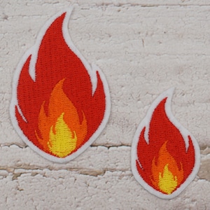 Könnte beinhalten: Zwei gestickte Aufnäher in Form von Flammen. Der größere Aufnäher ist etwa 7,6 cm hoch, der kleinere etwa 5 cm. Die Flammen sind rot, orange und gelb, mit einem weißen Rand. Diese Aufnäher eignen sich für Kleidung oder Accessoires.