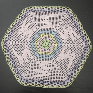 Könnte beinhalten: Eine gehäkelte Deckchen mit sechseckiger Form und einem mehrfarbigen Zentrum. Die Deckchen ist mit einem zarten, durchbrochenen Muster gearbeitet und hat eine Farbpalette aus Hellrosa, Hellblau, Hellgrün und Gelb.