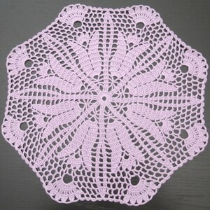 May include: A delicate lavender crochet doily with a circular design and a scalloped edge.
