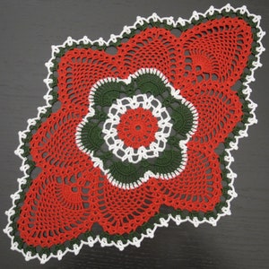 May include: A red, green, and white crocheted doily with a circular design in the center.