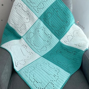 May include: A crocheted baby blanket with a white and teal color scheme. The blanket is made up of squares with a repeating pattern of a heart shape.