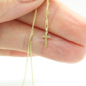 May include: A gold chain necklace with a small gold cross pendant.