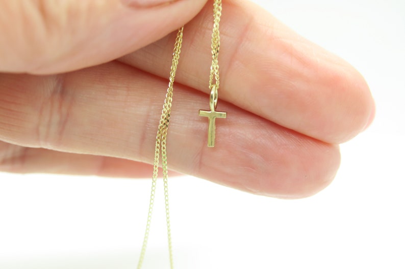 May include: A gold chain necklace with a small gold cross pendant.