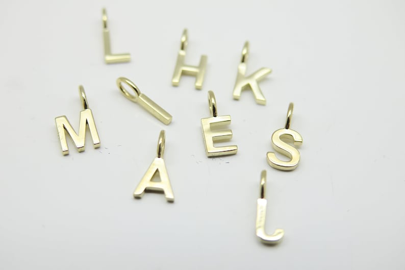 May include: A set of gold letter charms, including the letters A, E, H, J, K, L, M, and S. The charms are perfect for adding a personalized touch to jewelry.