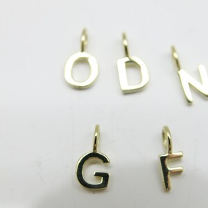 May include: Six gold-colored metal letter charms, each with a loop for attaching to a necklace or bracelet. The letters are O, D, N, G, and F.