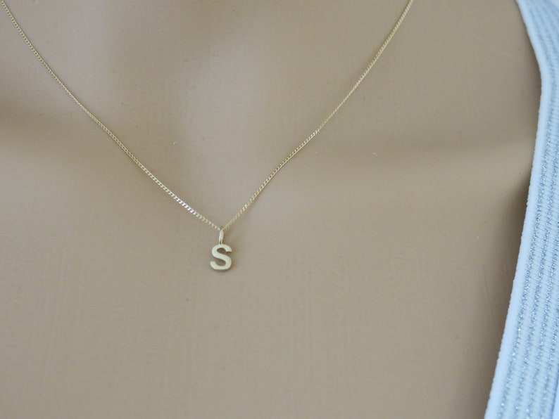 May include: A gold chain necklace with a small letter 'S' pendant.