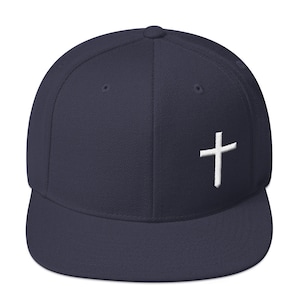 May include: A navy blue baseball cap with a white embroidered cross on the front.