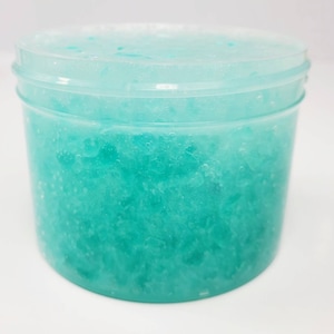 May include: A clear plastic jar filled with a light blue, sparkly slime.