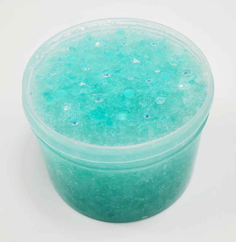 May include: A clear plastic container filled with teal blue slime with iridescent glitter.