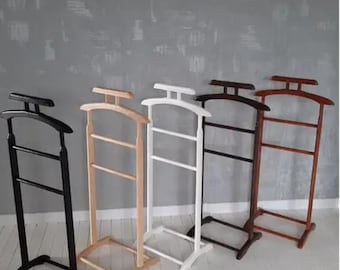 May include: Four wooden coat racks in different colors: black, natural wood, white, and brown. Each rack has three horizontal bars and a curved base.