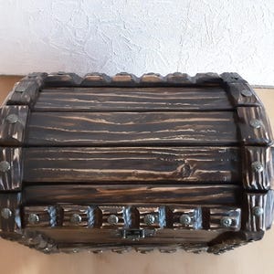 May include: A wooden treasure chest with a dark brown stain and metal accents. The chest has a hinged lid and a decorative metal clasp.