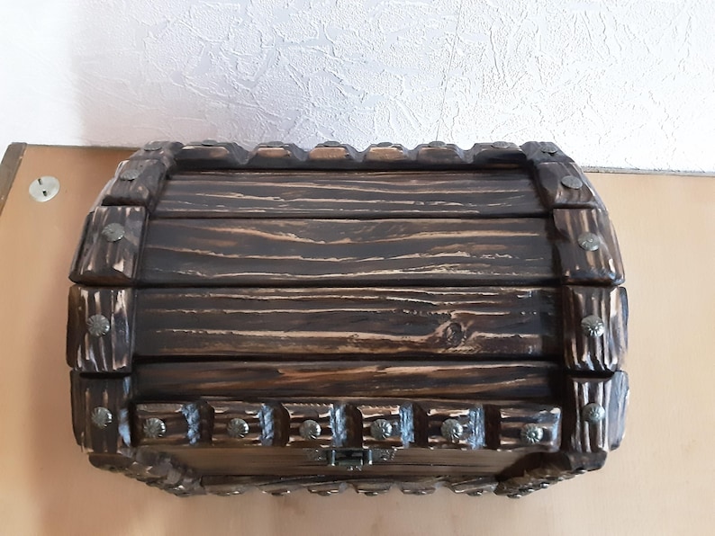 May include: A wooden treasure chest with a dark brown stain and metal accents. The chest has a hinged lid and a decorative metal clasp.