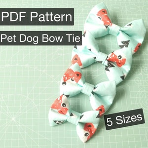 May include: A PDF pattern for a pet dog bow tie. The pattern comes in five sizes and features a turquoise bow tie with a red fox print. The bow ties are displayed on a green cutting mat.