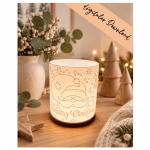 Pode incluir: Uma luminária cilíndrica branca com uma ilustração de linhas do Pai Natal, estrelas e corações, com o texto Merry Christmas na base. A lâmpada emite um brilho quente a partir do interior e assenta numa base circular escura.