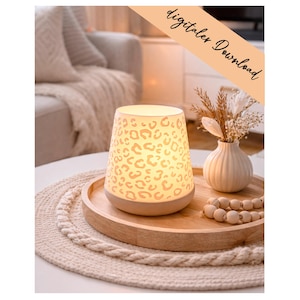 May include: A glowing, cylindrical lamp with a beige base and a cream-colored shade featuring a leopard print design. The lamp sits on a wooden tray with a small white vase and a strand of wooden beads. The text "digitales Download" is in the upper right corner.