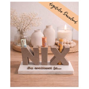 Puede incluir: Un expositor de hormigón gris con las letras NIX, con tres tubos de papel enrollados insertados en la parte superior de las letras. El bloque se asienta sobre una base rectangular blanca con el texto Du wolltest ja... en relieve en el frente.