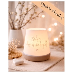 Könnte beinhalten: Eine leuchtende, weiß-beige Nachttischlampe mit dem Text "Schön, dass es dich gibt" und einem Herzsymbol. Die Lampe steht auf einer neutralfarbenen Oberfläche, mit einer weißen Vase und dekorativen Elementen im Hintergrund. Der Text "digitaler Download" ist ebenfalls sichtbar.