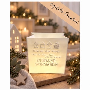 Könnte beinhalten: Eine weiße, quadratische Papierlaterne mit einer handgezeichneten Hausillustration und dem deutschen Text: Das ist das Haus... Ach ihr wisst doch was ich meine! ENTSPANNTE WEIHNACHTEN. Die Laterne ist von innen beleuchtet und strahlt ein sanftes Licht aus.