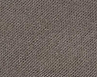 May include: A close-up shot of a plain fabric in a muted brown shade. The material has a diagonal ribbed texture, giving it a subtle pattern. The lighting is even, showing the details of the weave.
