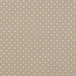 May include: Beige fabric with a white polka dot pattern. The fabric is measured with a ruler in centimetres.