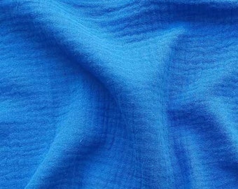 May include: A close-up of a blue fabric with a textured, crinkled surface. The fabric is soft and has a slightly wrinkled appearance.