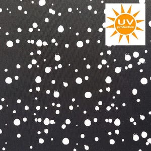 Può includere: Tessuto nero con un motivo a pois bianchi. Il tessuto ha un'etichetta di protezione UV.