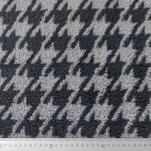 Könnte beinhalten: Nahaufnahme eines grauen und schwarzen Stoffes mit Hahnentrittmuster. Der Stoff hat eine flauschige Textur.