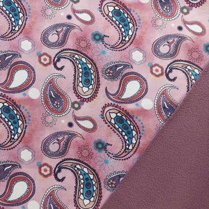 Op de afbeelding: Roze stof met een paisley-patroon. De stof heeft een zachte, pluche textuur aan de achterkant.