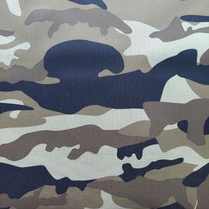 Könnte beinhalten: Tarnstoff mit einem Muster aus braunen, beigen und dunkelblauen Formen. Der Stoff hat eine strukturierte Oberfläche.