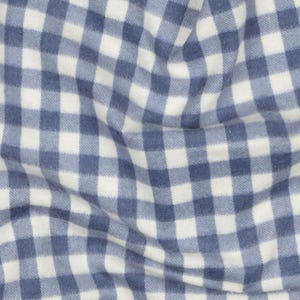 Op de afbeelding: Close-up van een blauw-wit geruite stof. De stof heeft een zachte, getextureerde uitstraling met een klassiek ruitpatroon. De vierkanten zijn even groot en creëren een visueel aantrekkelijk ontwerp, geschikt voor diverse textieltoepassingen.