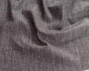 May include: A dark charcoal grey fabric with a visible woven texture and subtle white flecks throughout. The material features a dense, slightly coarse weave with natural folds and drapes, showing a raw, unfinished edge with loose threads at the bottom.