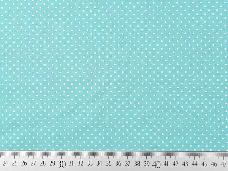 Op de afbeelding: Een turquoise stof met witte stippen. De stof is gemeten in inches.
