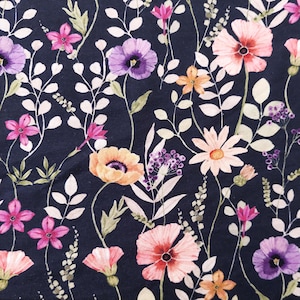 May include: A dark navy fabric with a watercolor floral pattern. The design features various flowers in shades of pink, purple, and orange, along with white and green foliage. The flowers are scattered across the fabric.
