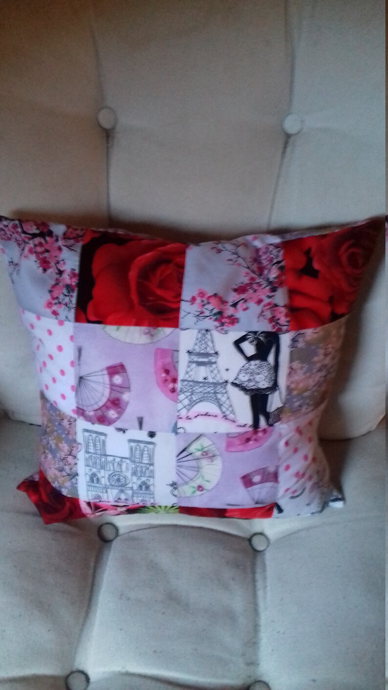 Puede incluir: Una almohada de patchwork con una variedad de dise&ntilde;os, que incluyen una rosa roja, un patr&oacute;n floral rosa, una Torre Eiffel en blanco y negro y un edificio blanco con una torre de reloj. La almohada est&aacute; hecha de tela y tiene un fondo blanco.