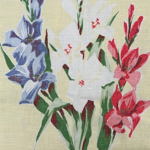 May include: A floral pattern featuring gladiolus flowers in shades of blue, white, and red. The flowers have green leaves and are set against a light yellow background. The fabric has a textured appearance.