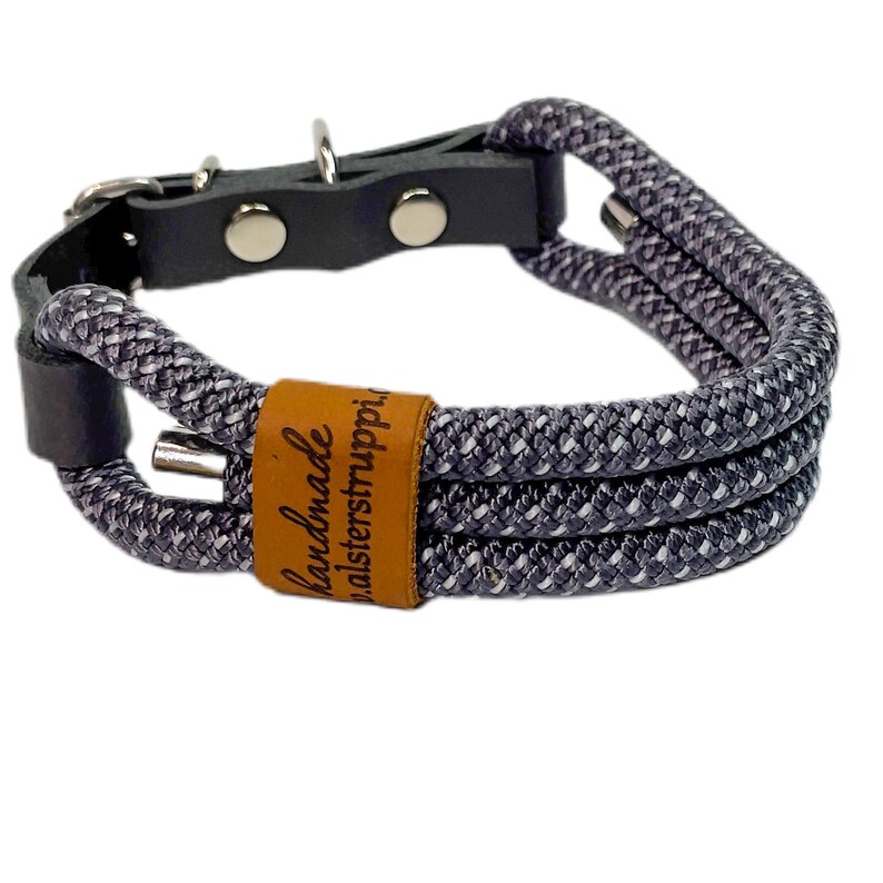 May include: A gray and white rope dog collar with a brown leather patch that says "handmade alsterstruppi".