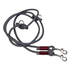May include: A gray and black double dog leash with red accents and two silver clips.