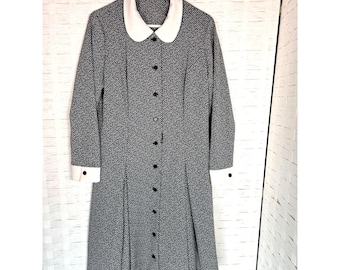 May include: A black and white patterned dress with a white collar and cuffs. The dress has a button-up front and a flared skirt.