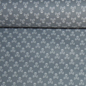 Könnte beinhalten: Grauer Stoff mit einem sich wiederholenden Muster aus weißen Totenköpfen und Knochen.